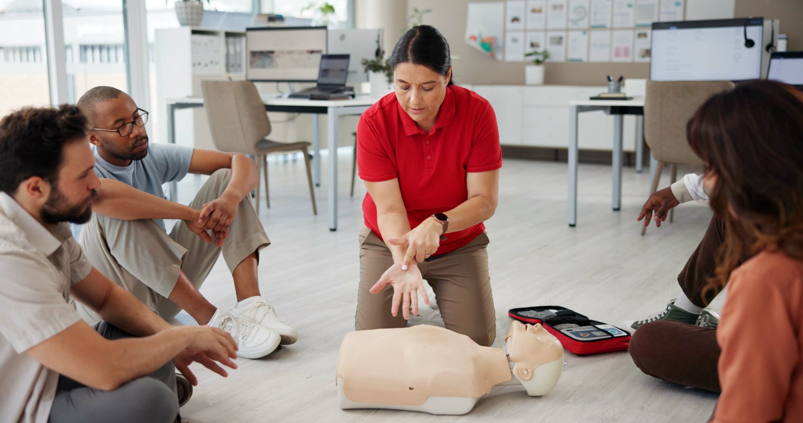 First aid, cpr training and people with mannequin for safety compliance or healthcare. Paramedic course, medical demonstration and teaching emergency rescue technique with hand in business office.